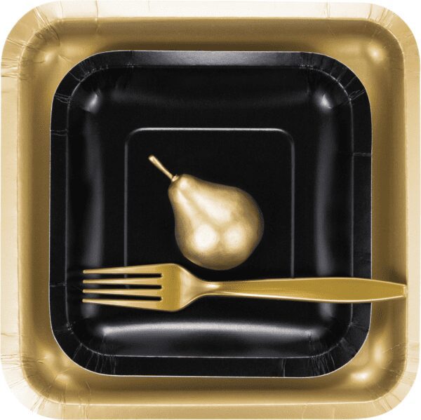 A black and gold paper plate with fork, knife and pear.