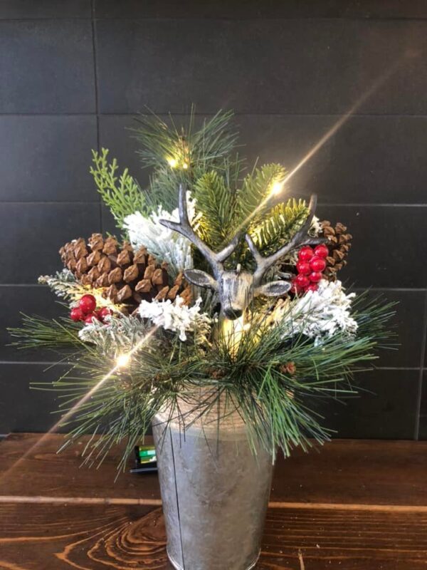 A christmas arrangement of pine cones, berries and lights.