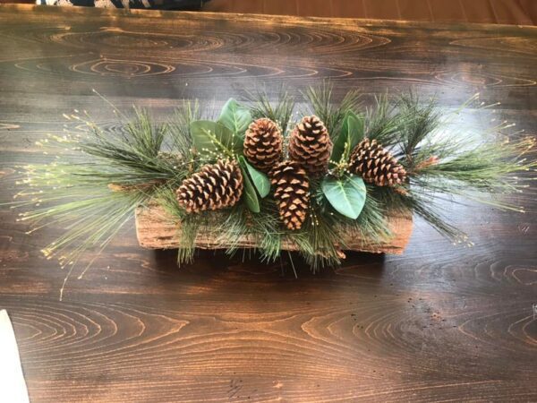 A wooden table with pine cones and greenery.