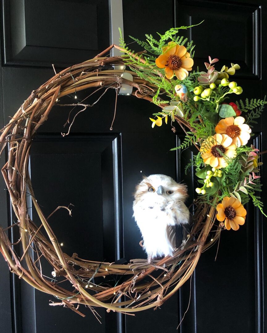 A wreath with flowers and branches on the front of it.