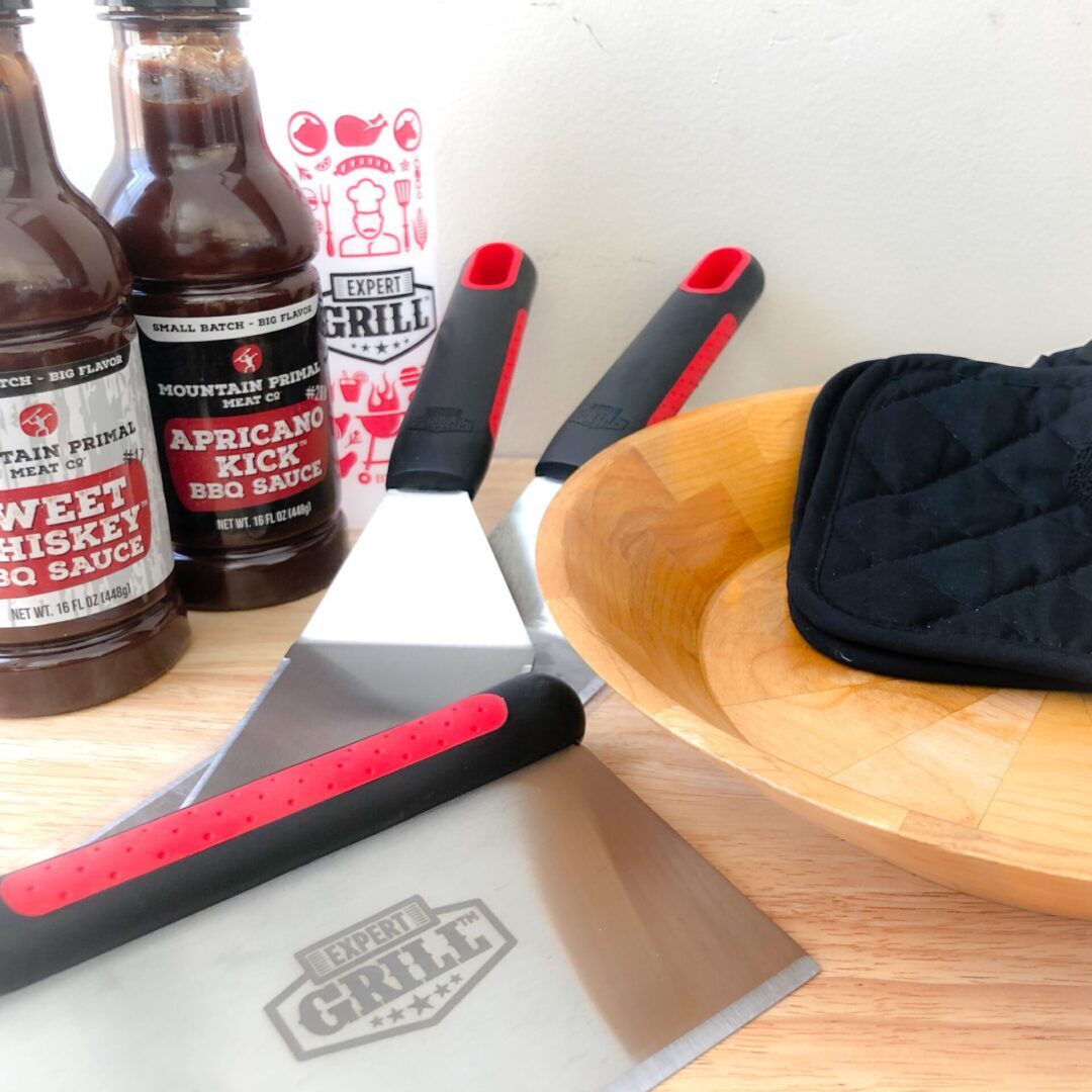 A table with beer, pizza cutter and cutting board.